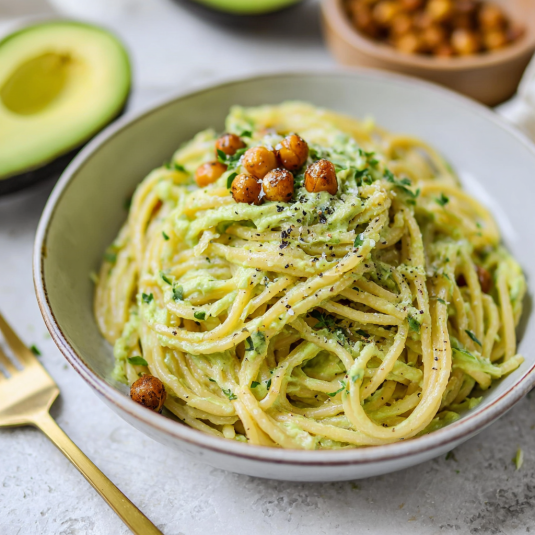 Una ciotola di spaghetti con noci e avocado.