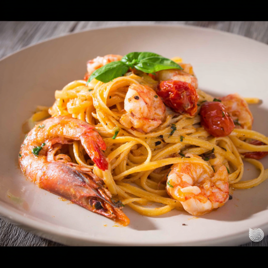 Un piatto di spaghetti con tomate e frullato di pesce.