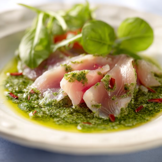Piatto con pesce, erbe e salsa verde.
