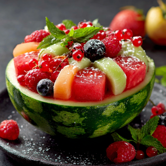 Una tazza di frutta con mirtilli, arance, pesche, melo, kiwi e frutta di bosco.