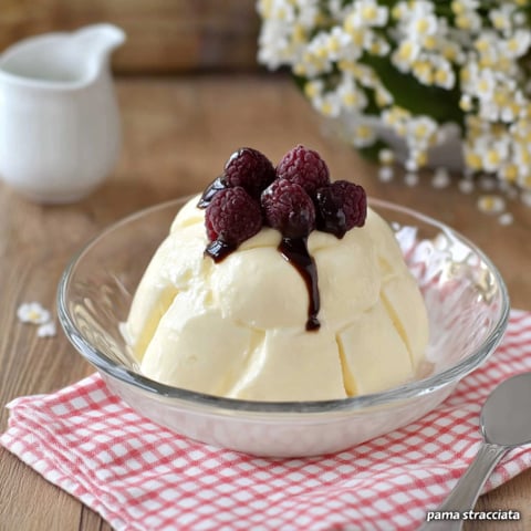 Un bicchiere di crema con frutta su di esso.