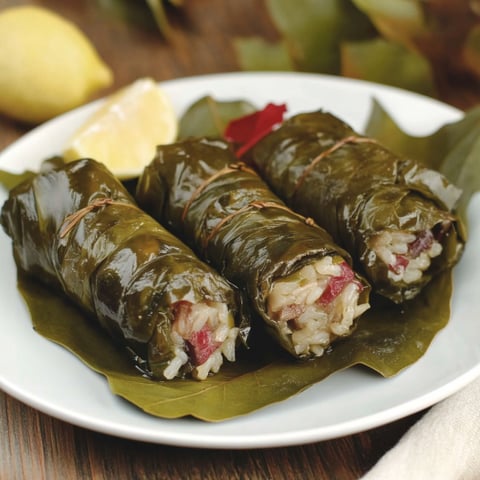 Due pezzi di pollo avvolti in foglie di basilico.