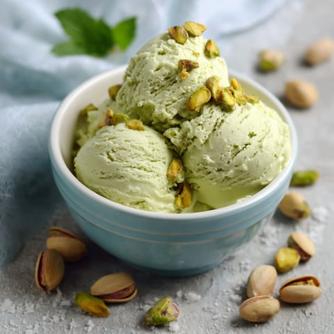 Un bicchiere di gelato con nocciole e semi di pistacchio.