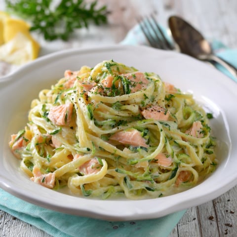 Una ciotola di spaghetti con pesce e verdure.