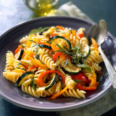 Una tavolata con un piatto di pasta e verdure.