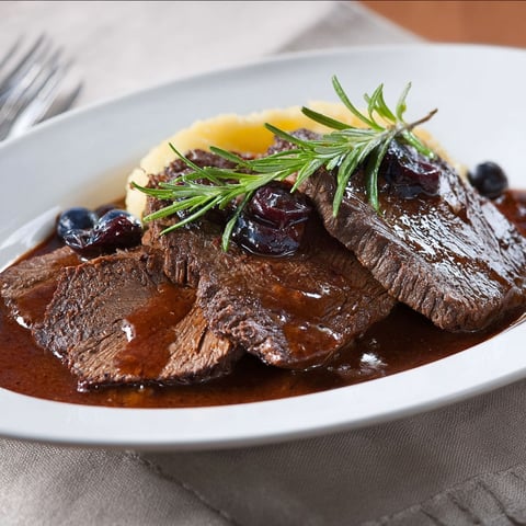 Un plateau de viande de bœuf à la sauce Barolo, avec des herbes et des baies.